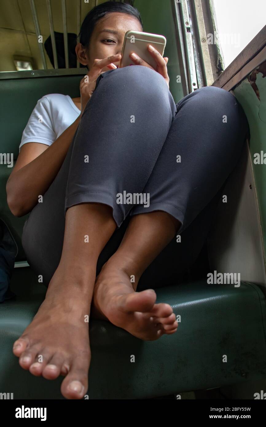 Une jeune femme avec téléphone mobile balade en petit train. Fille asiatique avec le smartphone se trouve à côté de la fenêtre ouverte au wagon rétro, la Thaïlande. Banque D'Images