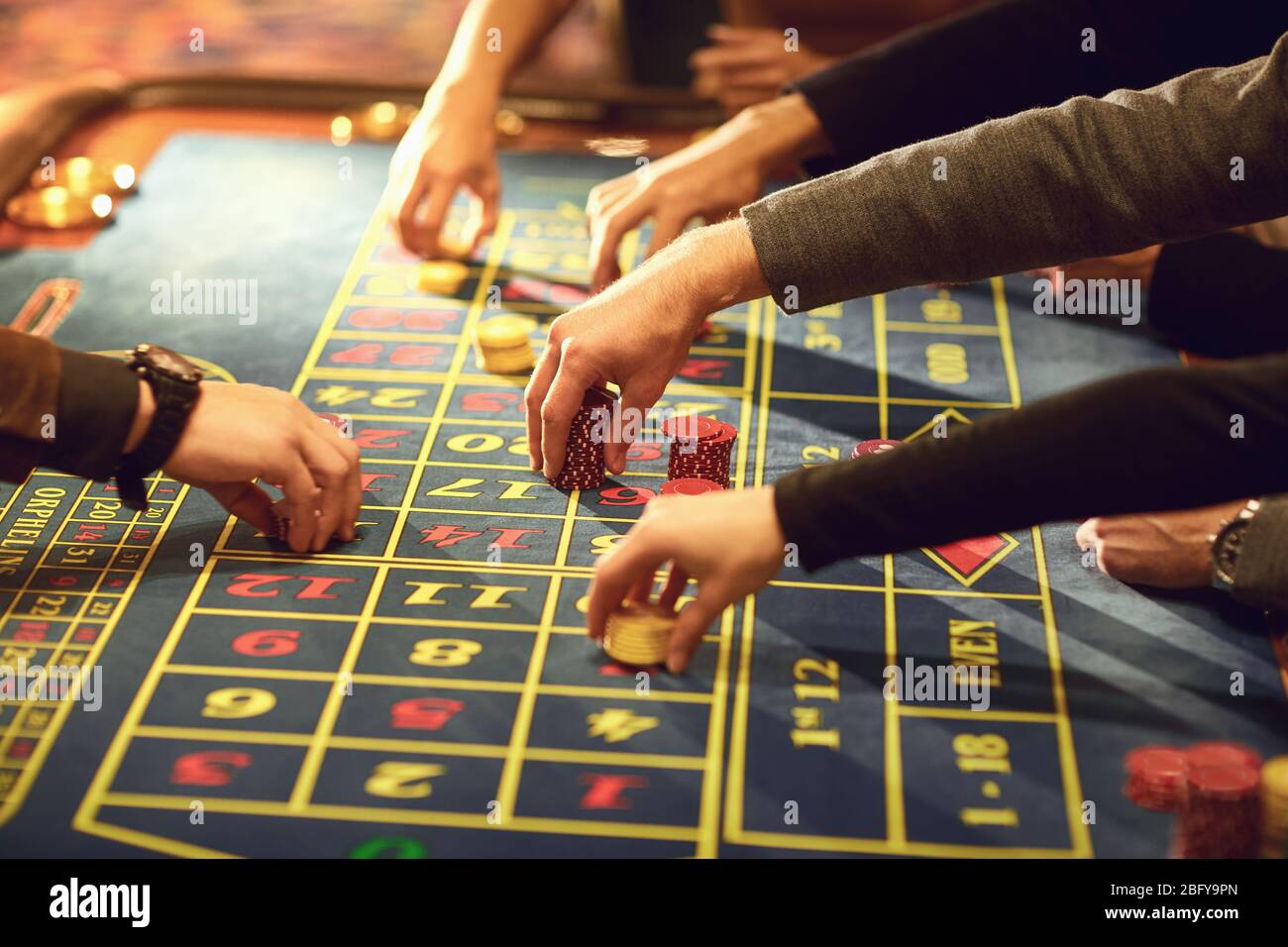 Gros plan des mains avec des jetons pour jouer sur une table de roulette de casino. Banque D'Images