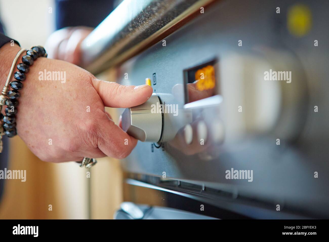 Gros plan d'une main masculine tenant le cadran rotatif d'un four à micro-ondes pour cuisiner des aliments dans la cuisine à la maison Banque D'Images