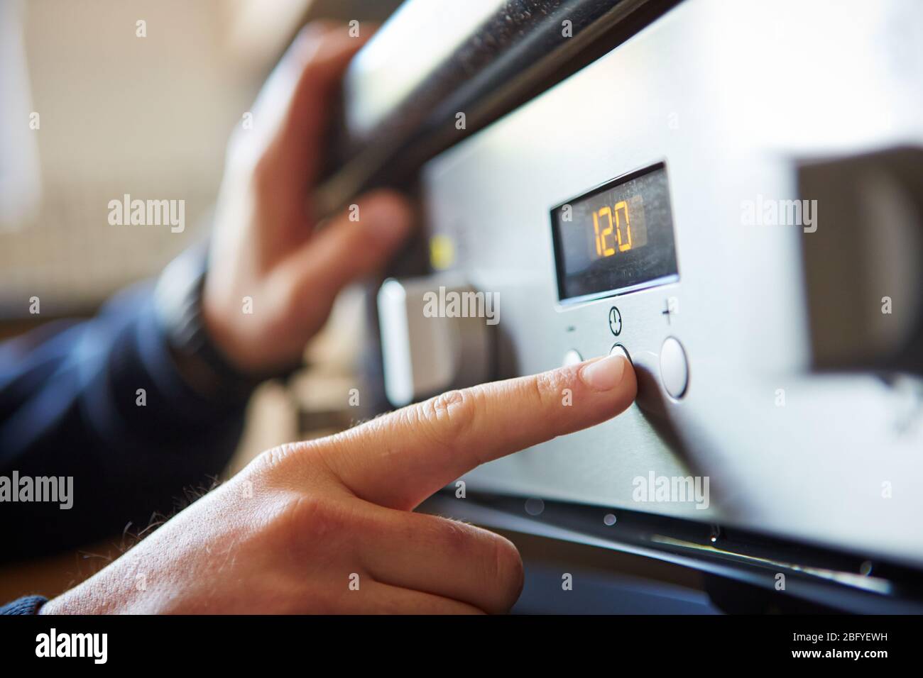 Gros plan d'une main masculine commençant un four à micro-ondes pour cuisiner des aliments dans la cuisine à la maison, en appuyant sur un bouton. Banque D'Images
