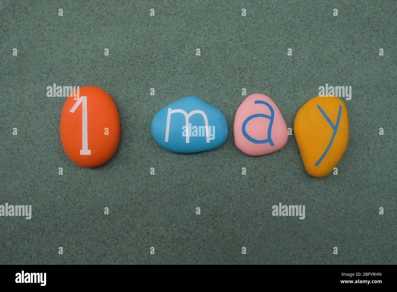 1 mai, date du calendrier composé de pierres multicolores sur sable vert Banque D'Images