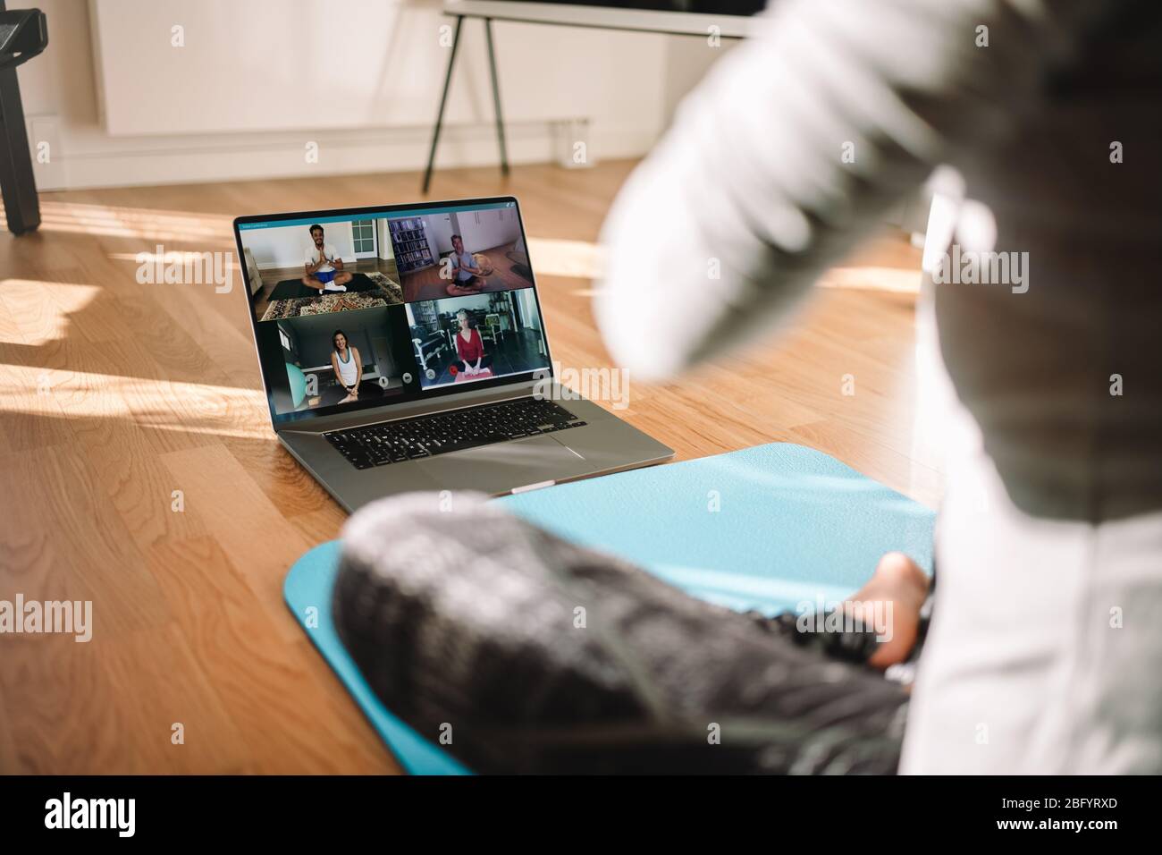 Vue d'une femme qui mène un cours virtuel de fitness avec un groupe de personnes à la maison lors d'une vidéoconférence. Instructeur de fitness prenant des cours de yoga en ligne ove Banque D'Images