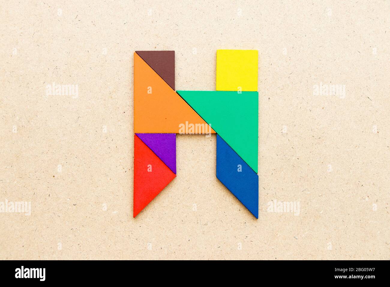 Puzzle en forme de lettre H en forme de tangram sur fond de bois Banque D'Images