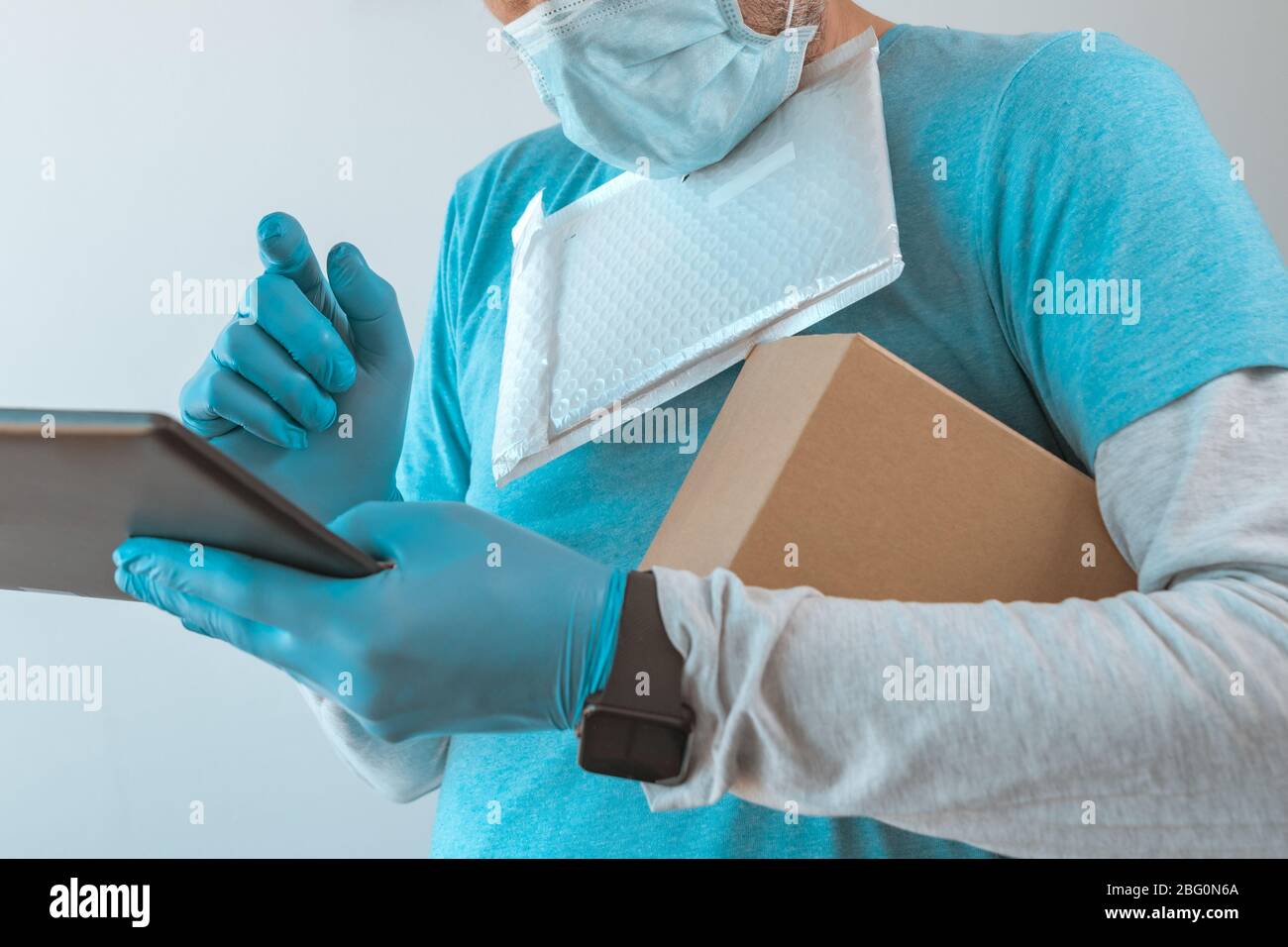 Homme de livraison avec des vêtements de protection utilisant une tablette numérique avec des gants de protection pendant une pandémie d'infection virale, foyer sélectif Banque D'Images