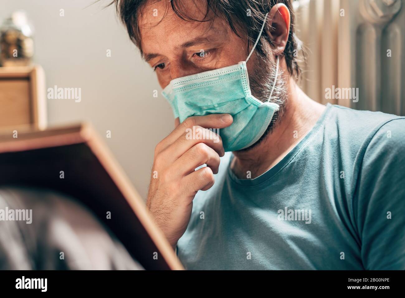 Livre de lecture de l'homme en quarantaine auto-isolée à la maison pendant la pandémie de virus Banque D'Images