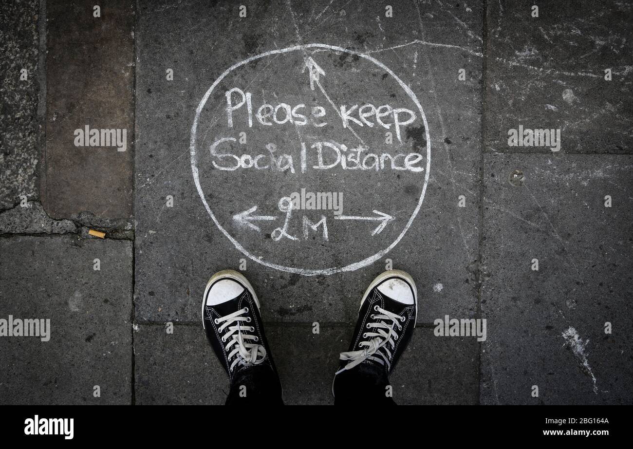 Dublin, Irlande - 19 avril 2020: Un message social distancing de deux mètres écrit dans la craie sur le pavé dans le centre-ville. Banque D'Images