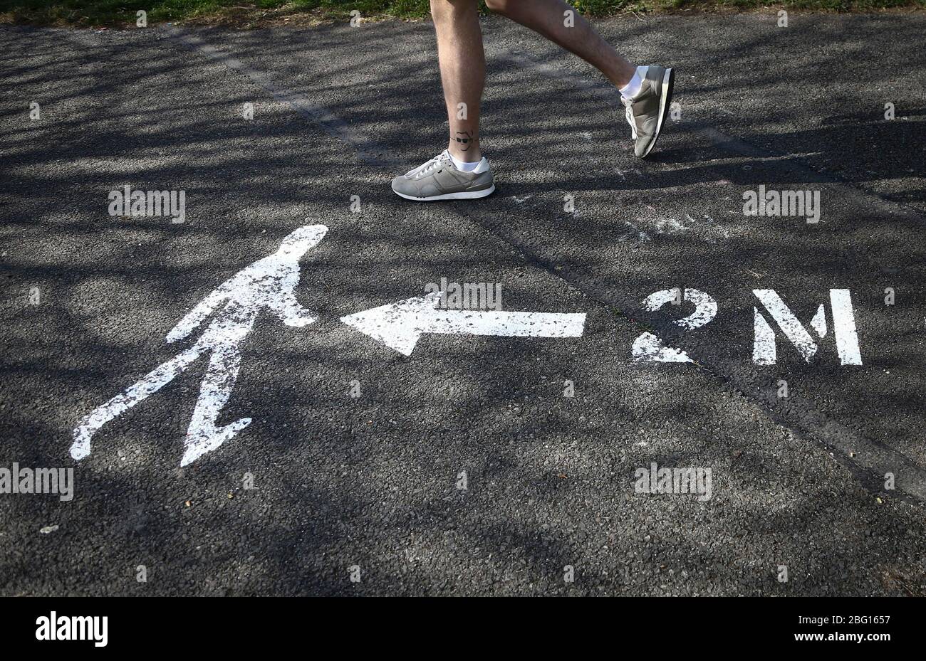 Dublin, Irlande - 19 avril 2020: Un jogger passant un message social distançant la santé publique sur le pavé de 2 mètres. Banque D'Images