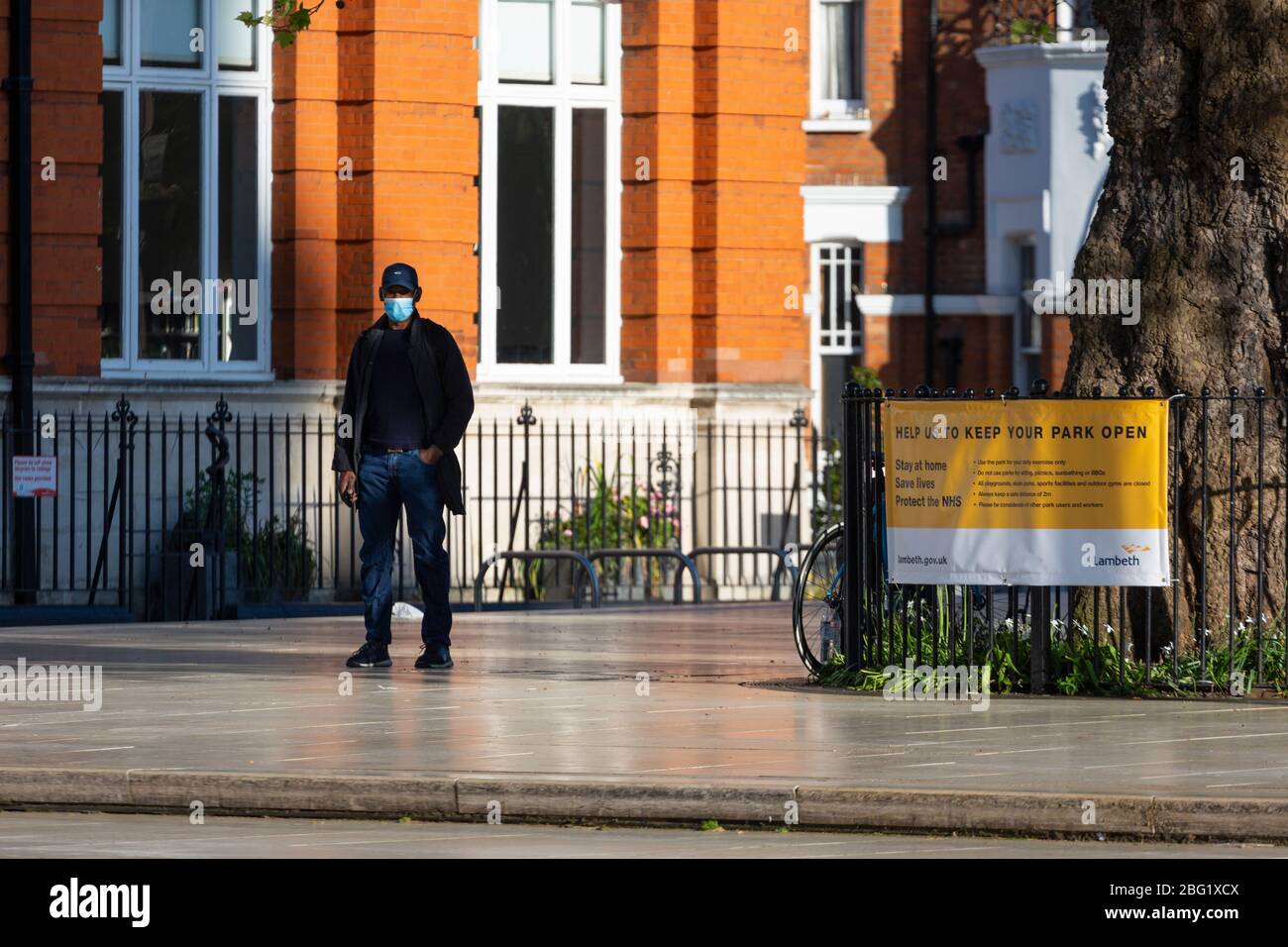 Un homme portant un masque de visage se tient à Windrush Square, Brixton, pendant le maintien de Londres en raison de la propagation de Covid-19, 19 avril 2020 Banque D'Images