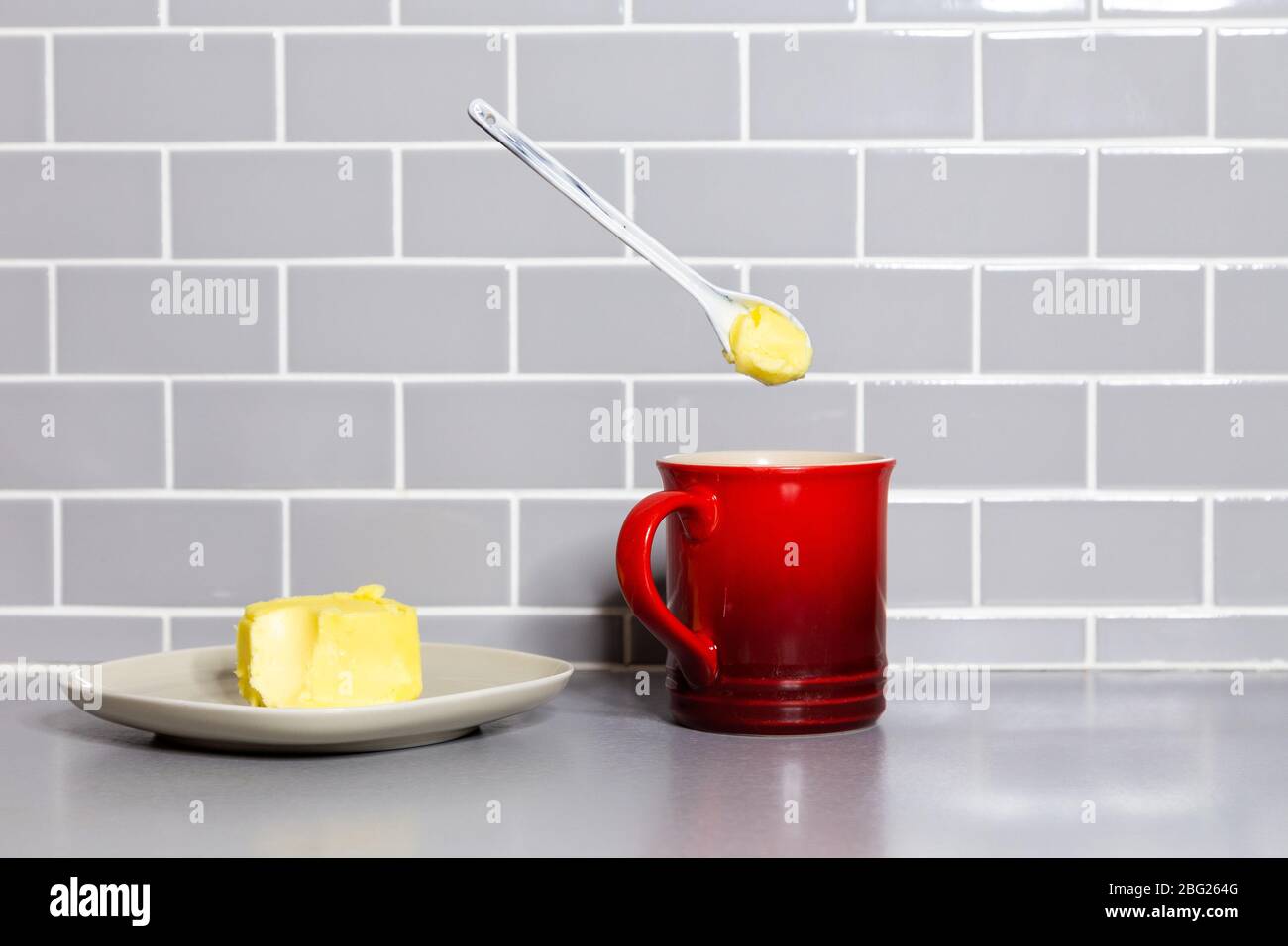 Une cuillère à café de beurre flottante avec une tasse de café rouge pour préparer du café à l'épreuve des balles. Banque D'Images