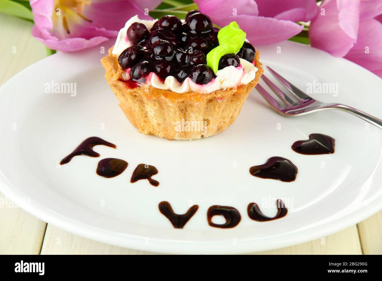 Gâteau sucré avec sauce au chocolat et au blackberry sur plaque, sur fond en bois Banque D'Images