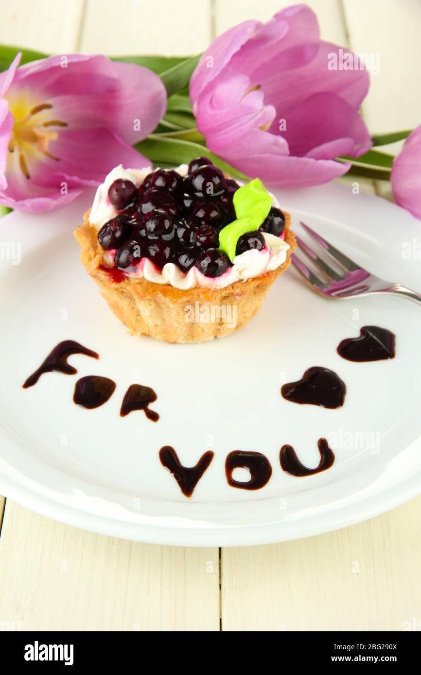 Gâteau sucré avec sauce au chocolat et au blackberry sur plaque, sur fond en bois Banque D'Images