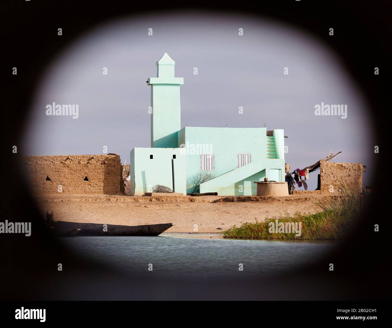 Minaret turquoise sur le fleuve Sénégal vu à travers un hublot sur le bateau antique de la rivière Bou el Mogdad. Banque D'Images