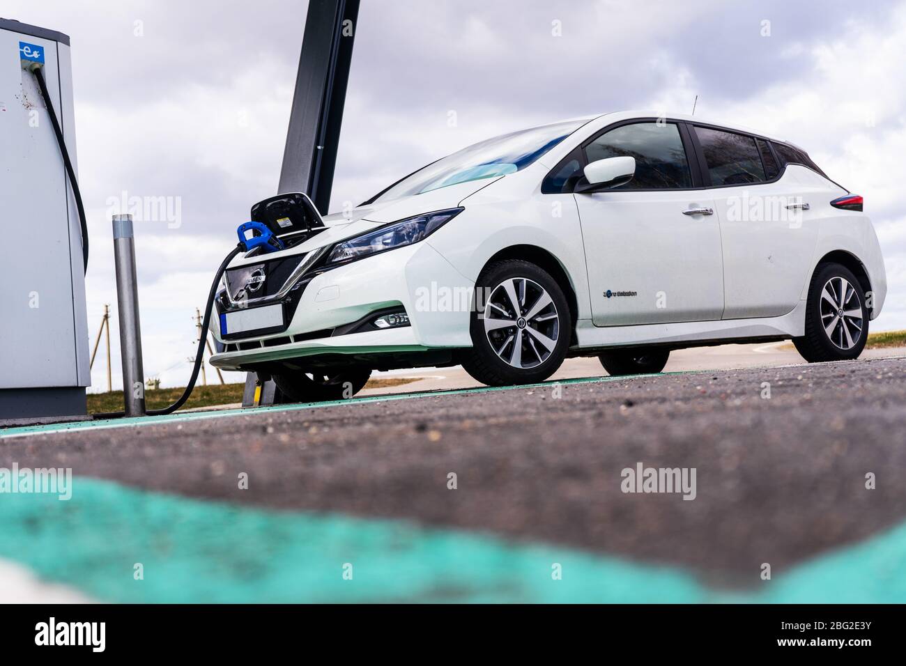 Point de charge de voiture électrique avec Nissan Leaf connecté. Station de parking et de recharge pour véhicules électriques. Banque D'Images