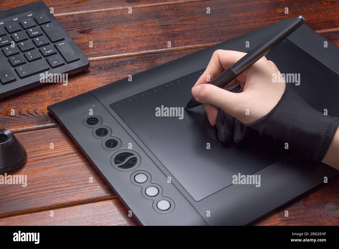 La main s'appuie sur une tablette graphique. Freelance, concepteur, Illustrator. Technologie, travail à distance, externalisation. Gant et stylo pour tablette graphique. Graphique Banque D'Images