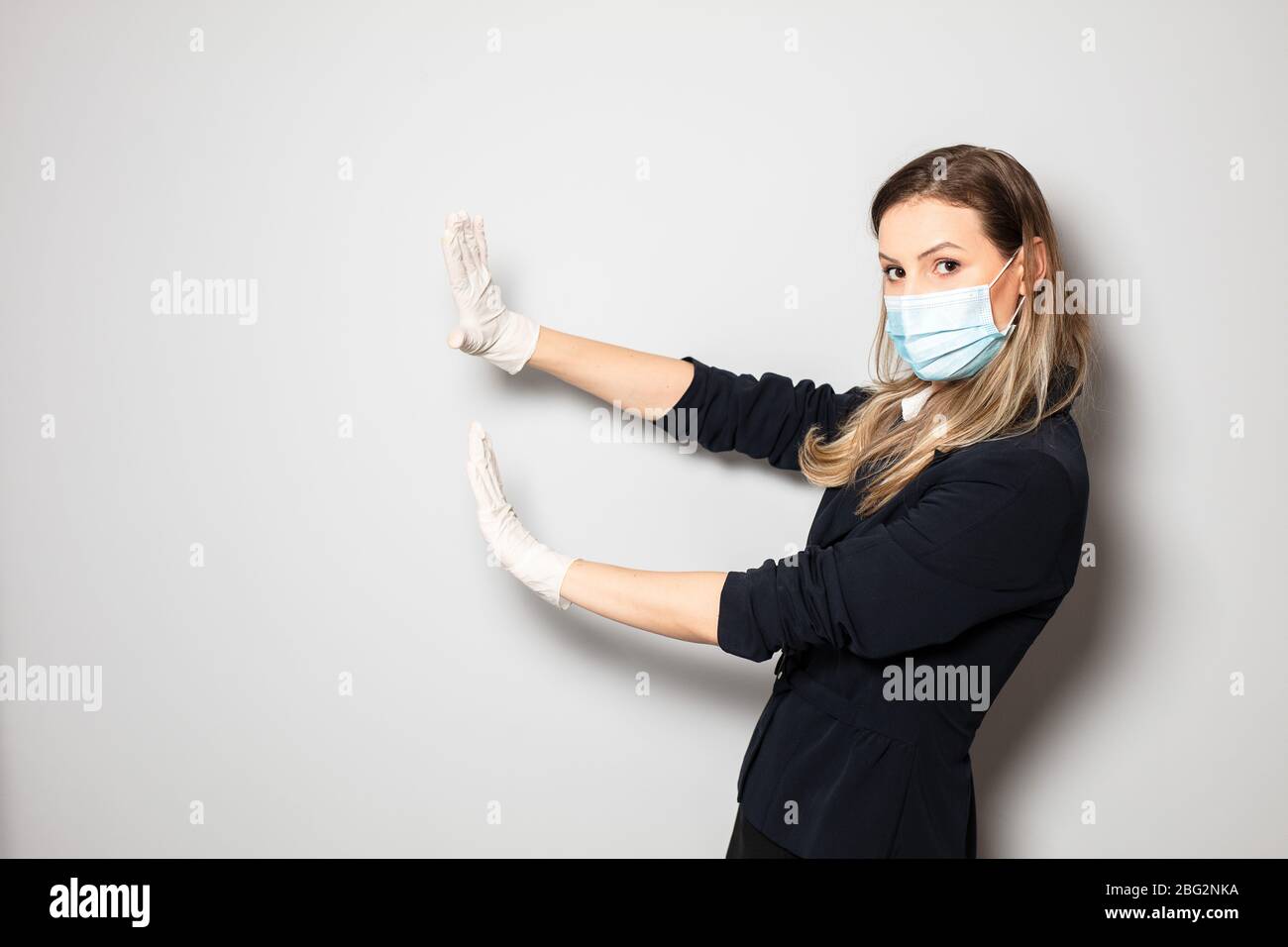 femme avec protection de masque et gants poussant quelque chose ou en mettant un arrêt de l'infection par le virus Banque D'Images