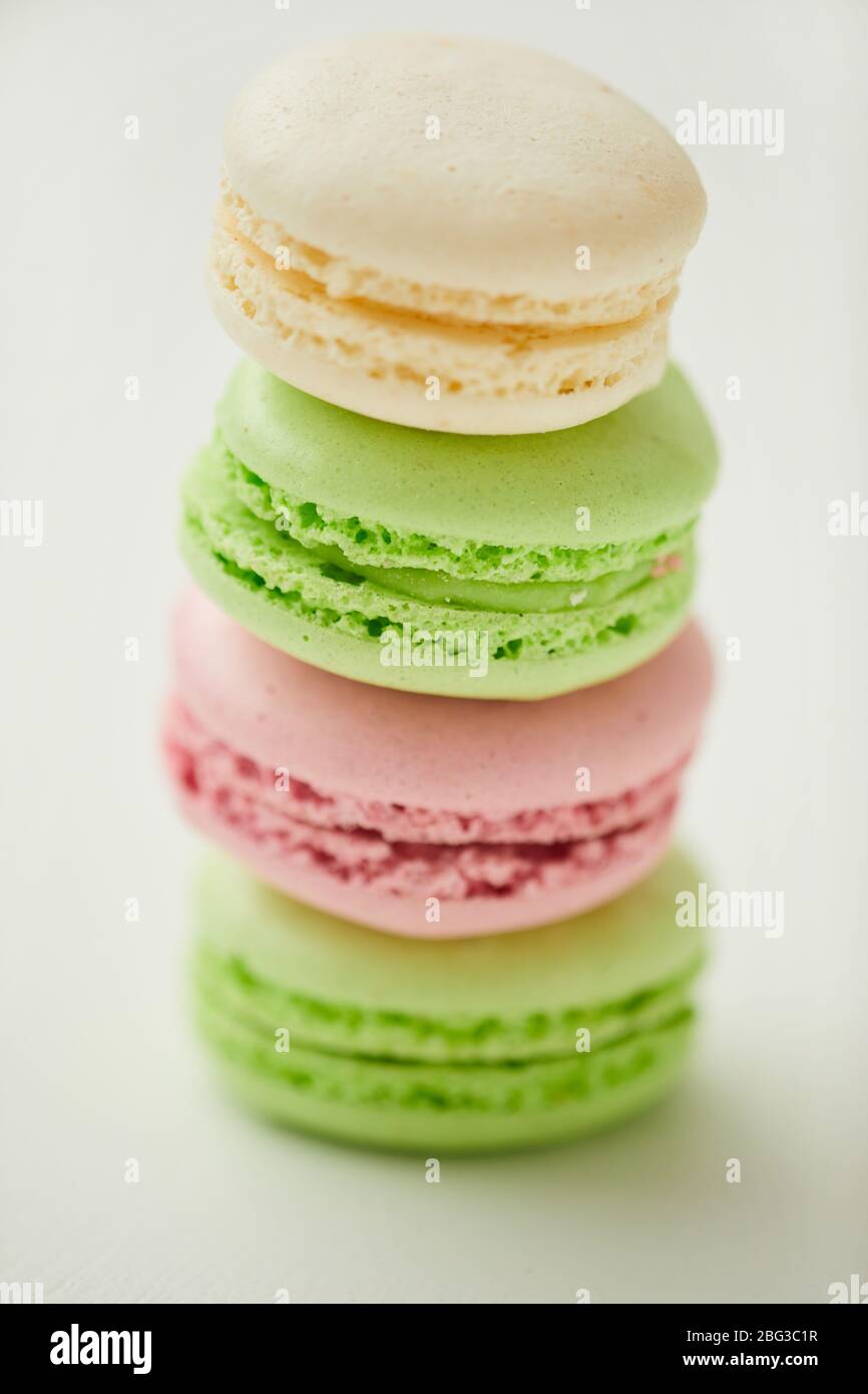 Gros plan vertical de délicieux macarons aux couleurs pastel empilés en ligne sur fond blanc Banque D'Images