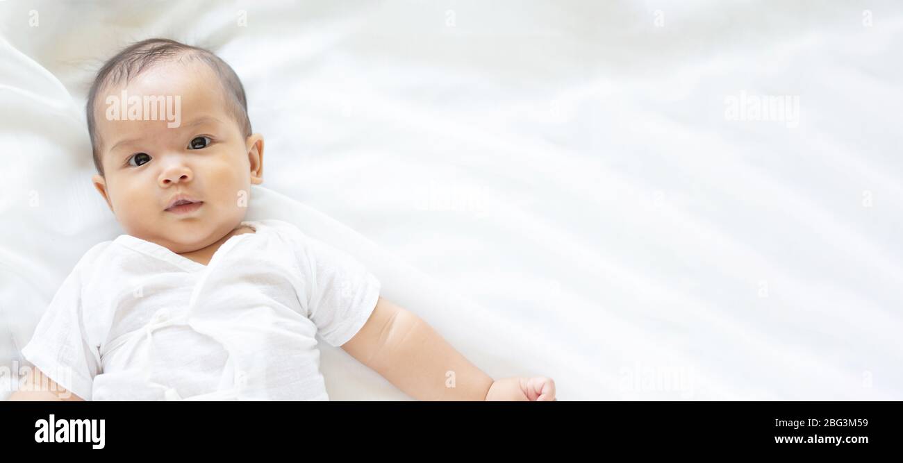 Mignon bébé nouveau-né fille dans couverture blanche sur lit de la crèche. Adorable nouveau-né petit garçon, ses yeux semblent être les gens de la famille, de la petite enfance, la nouvelle peau douce p Banque D'Images