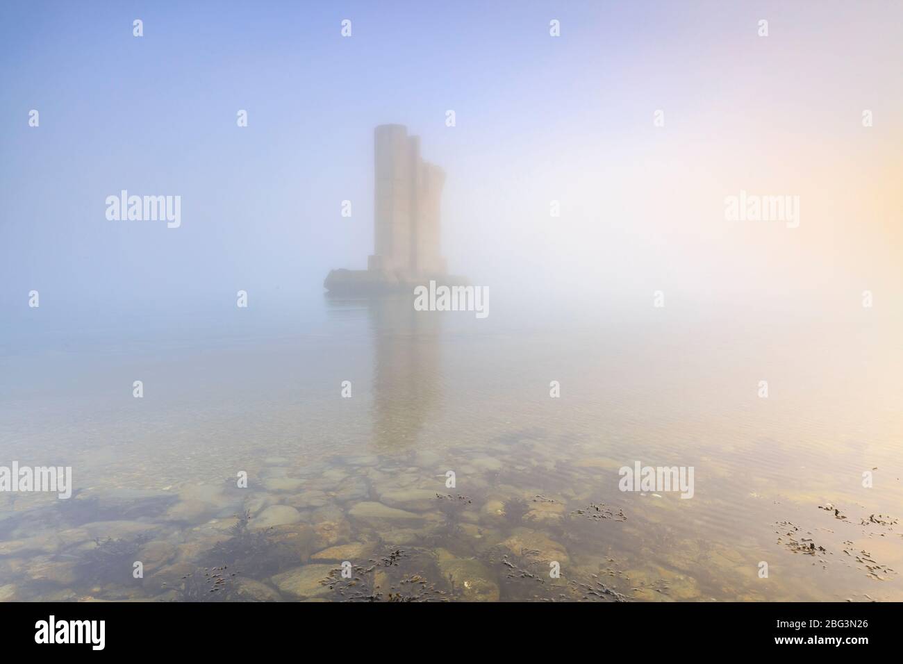 L'un des autres piliers de l'eidersperrwerk debout dans l'eau au cours d'un hiver brumeux dense lourd coucher de soleil sur le delta de la mer de tempête Banque D'Images