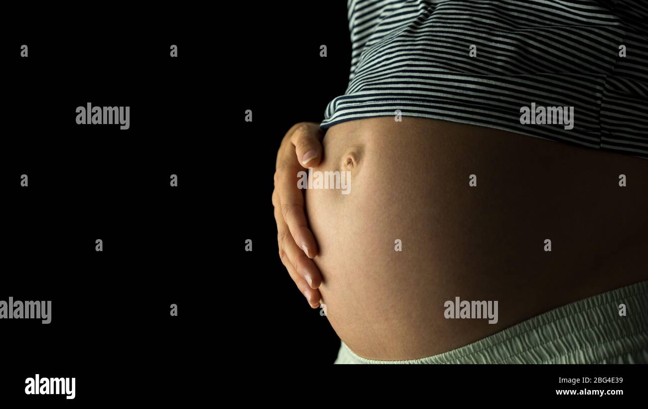 Gros Plan De 30 Semaines Ventre Enceinte Avec La Mere Qui S Occupe De Son Bebe A Naitre Sur Fond Noir Photo Stock Alamy