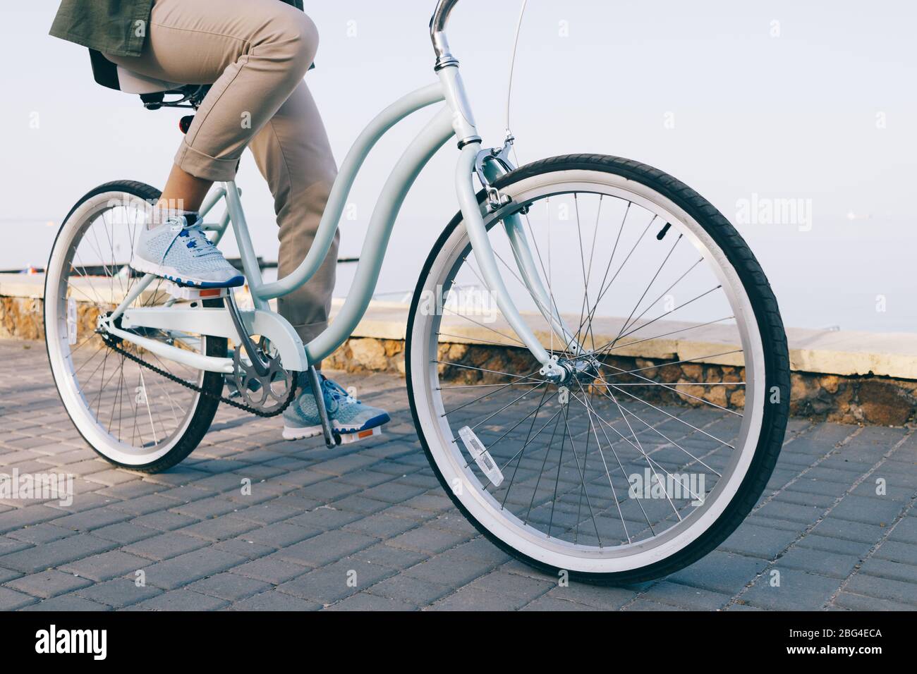 Une jeune femme de gros plan portant un pantalon beige décontracté fait ses courses à vélo d'époque. Banque D'Images