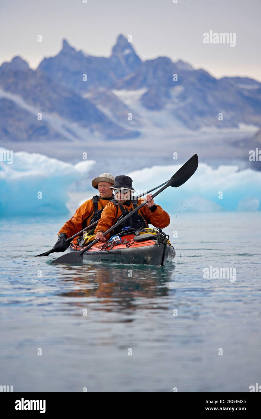 2 hommes voyageant sur un kayak de mer à travers les fjords de l'est du Groenland Banque D'Images