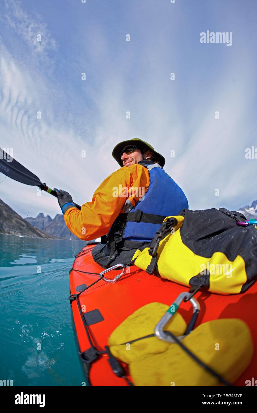 Homme voyageant sur un kayak de mer à travers les fjords de l'est du Groenland Banque D'Images