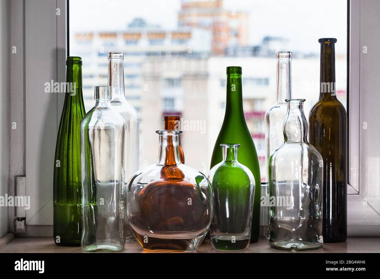 de nombreuses bouteilles vides sur le seuil de fenêtre et vue sur la ville par la fenêtre de la maison sur fond Banque D'Images