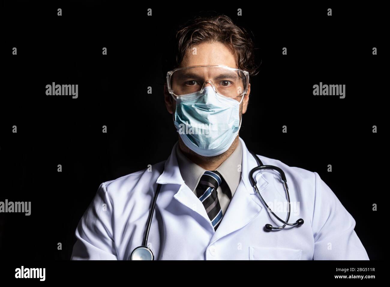 médecin homme portant un masque et des lunettes, fatigué de travailler avec covid-19 sur un fond noir. Banque D'Images