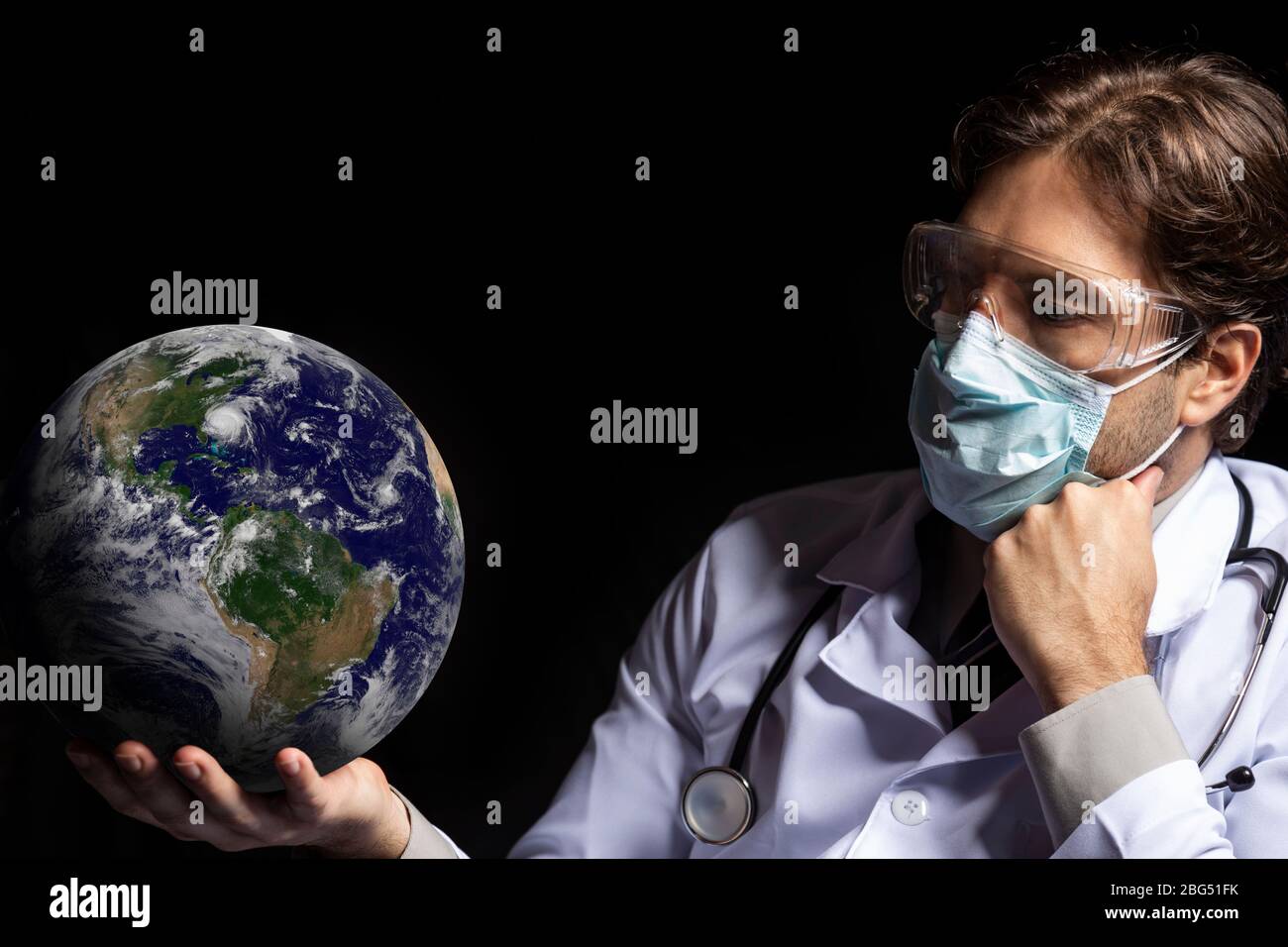 médecin homme portant un masque et des lunettes de protection avec la terre dans ses mains, fatigué de travailler avec covid-19 sur un fond noir. Banque D'Images