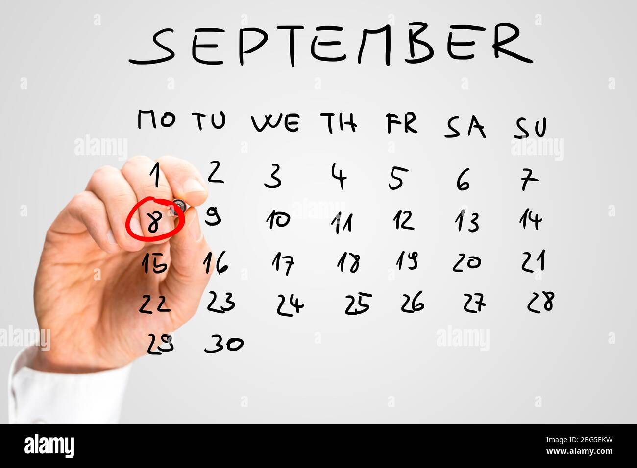 L'homme qui sonne le 8 septembre sur un calendrier manuscrit avec un marqueur rouge pour rappeler que la date est la Journée internationale de l'alphabétisation. Banque D'Images