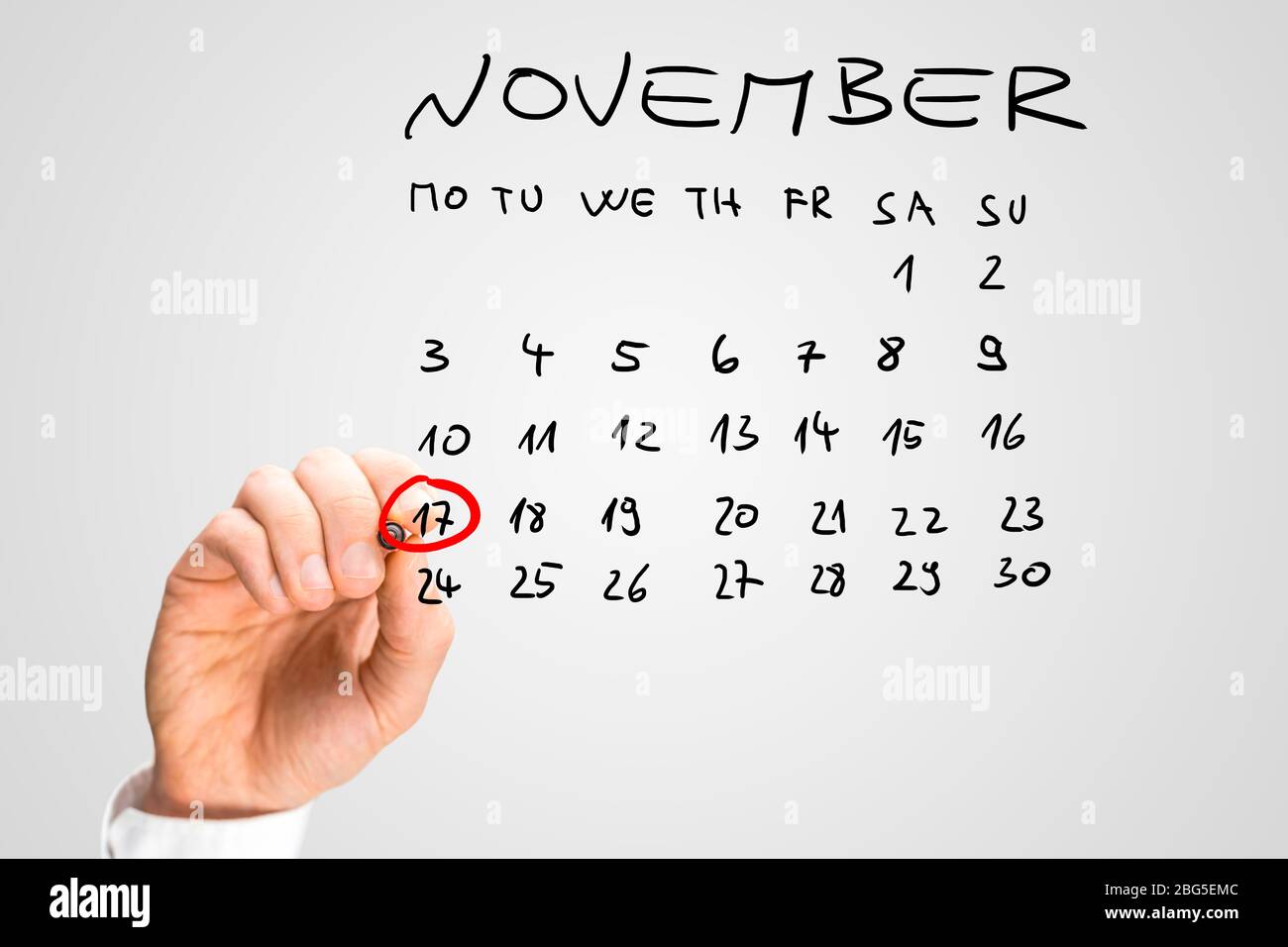 Gros plan de la main d'un homme qui sonnait le 17 novembre sur un calendrier manuscrit sur une interface virtuelle avec un marqueur rouge comme rappel de l'internat Banque D'Images