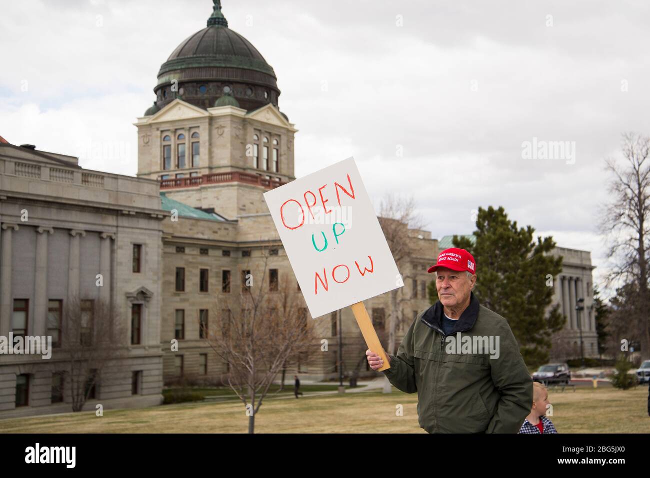 Helena, Montana - 19 avril 2020: Un citoyen senior protestant portant un chapeau rouge Make America Great à nouveau tenant un signe disant pour ouvrir le gove Banque D'Images