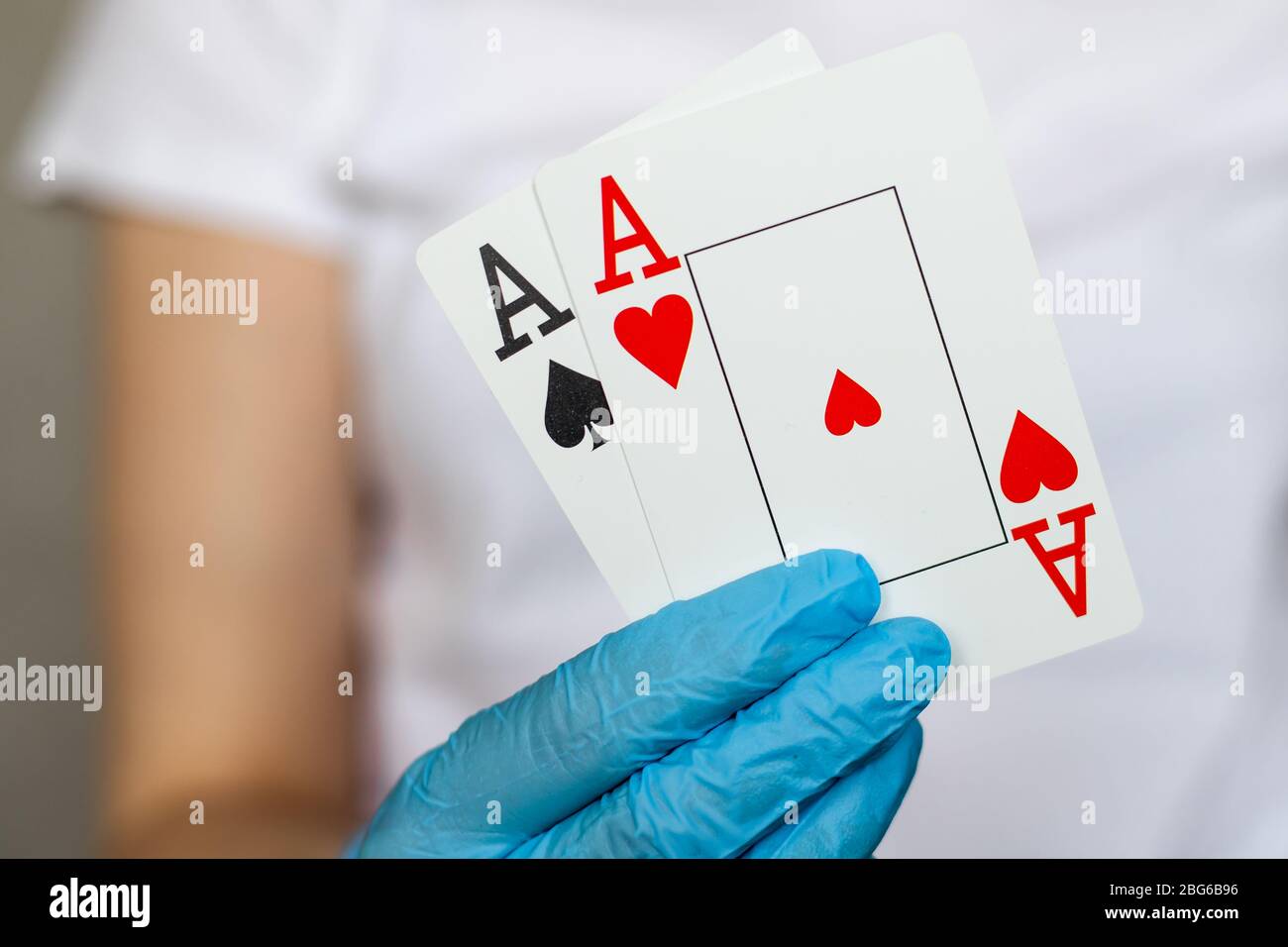 Jeune femme avec des gants de protection jetables tenant des cartes - paire d'as Banque D'Images