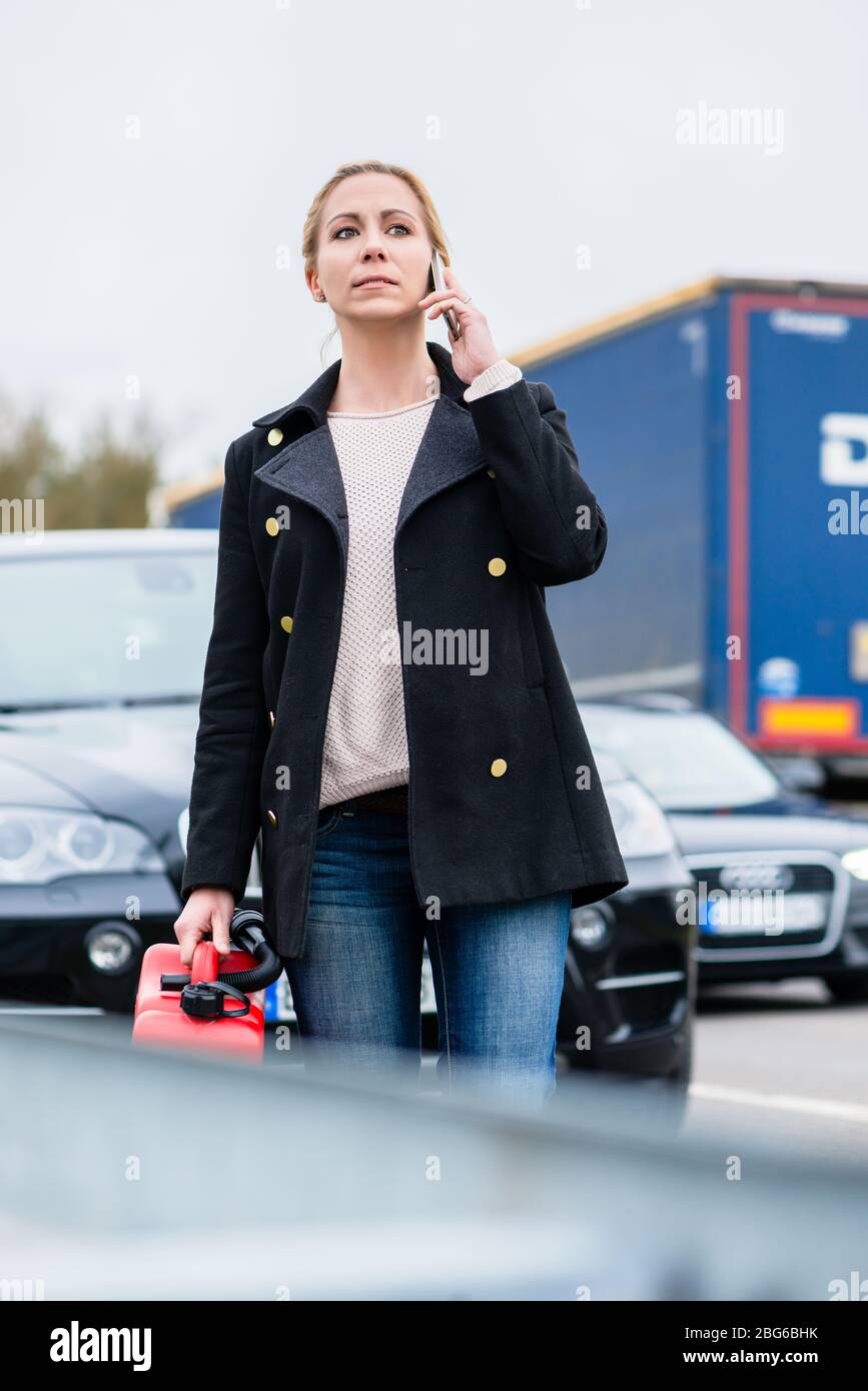 Femme en dehors de l'essence avec sa voiture de téléphone pour quelqu'un de la prendre Banque D'Images