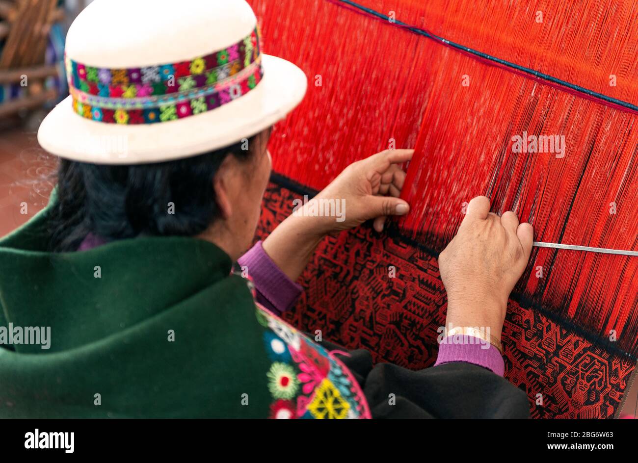 Femme autochtone dans les vêtements traditionnels tissant un tissu Jalq'a coloré à sucre, en Bolivie. Banque D'Images