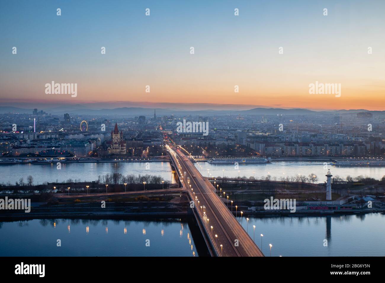 Vue panoramique sur Vienne le soir, Donau et Neue Donau avec pont Reichsbrücke au crépuscule, capitale autrichienne coucher de soleil Alpes fond Banque D'Images