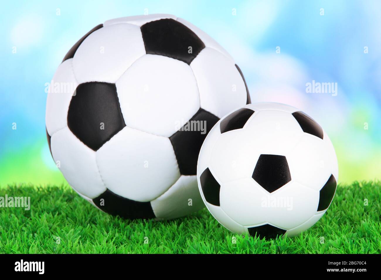 Ballons de football sur herbe verte sur fond lumineux Banque D'Images