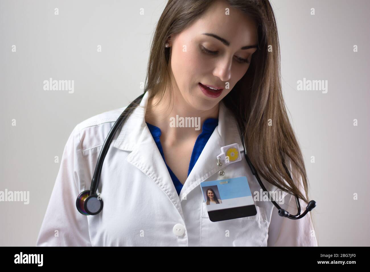 Médecin féminin sur fond gris. Manteau blanc, stéthoscope, badge visible. Médecin souriant Banque D'Images
