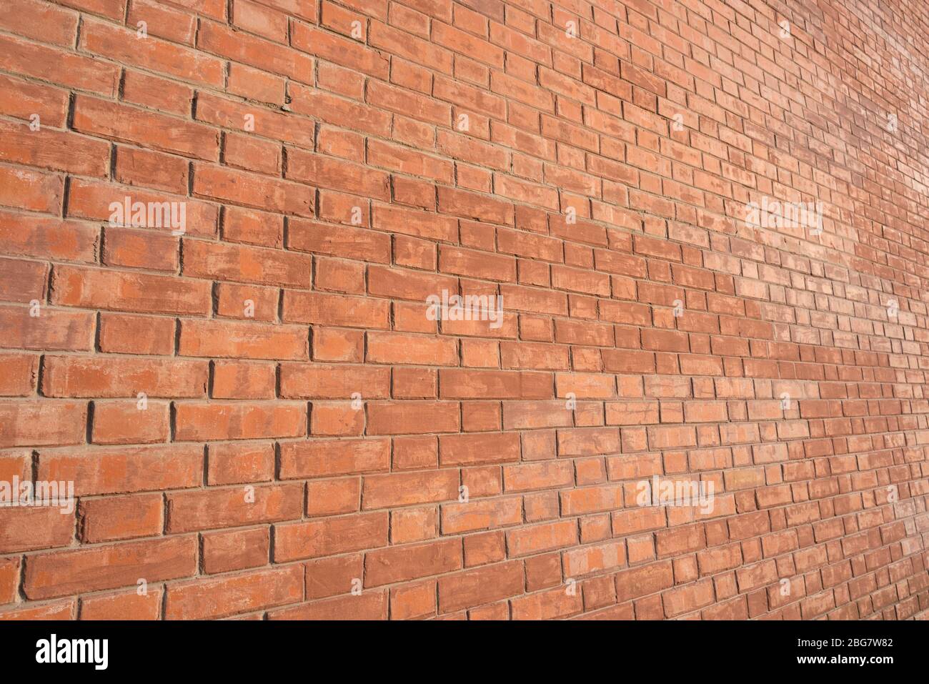 Mur de briques, vue inclinée, éclairé par une lumière chaude. Banque D'Images