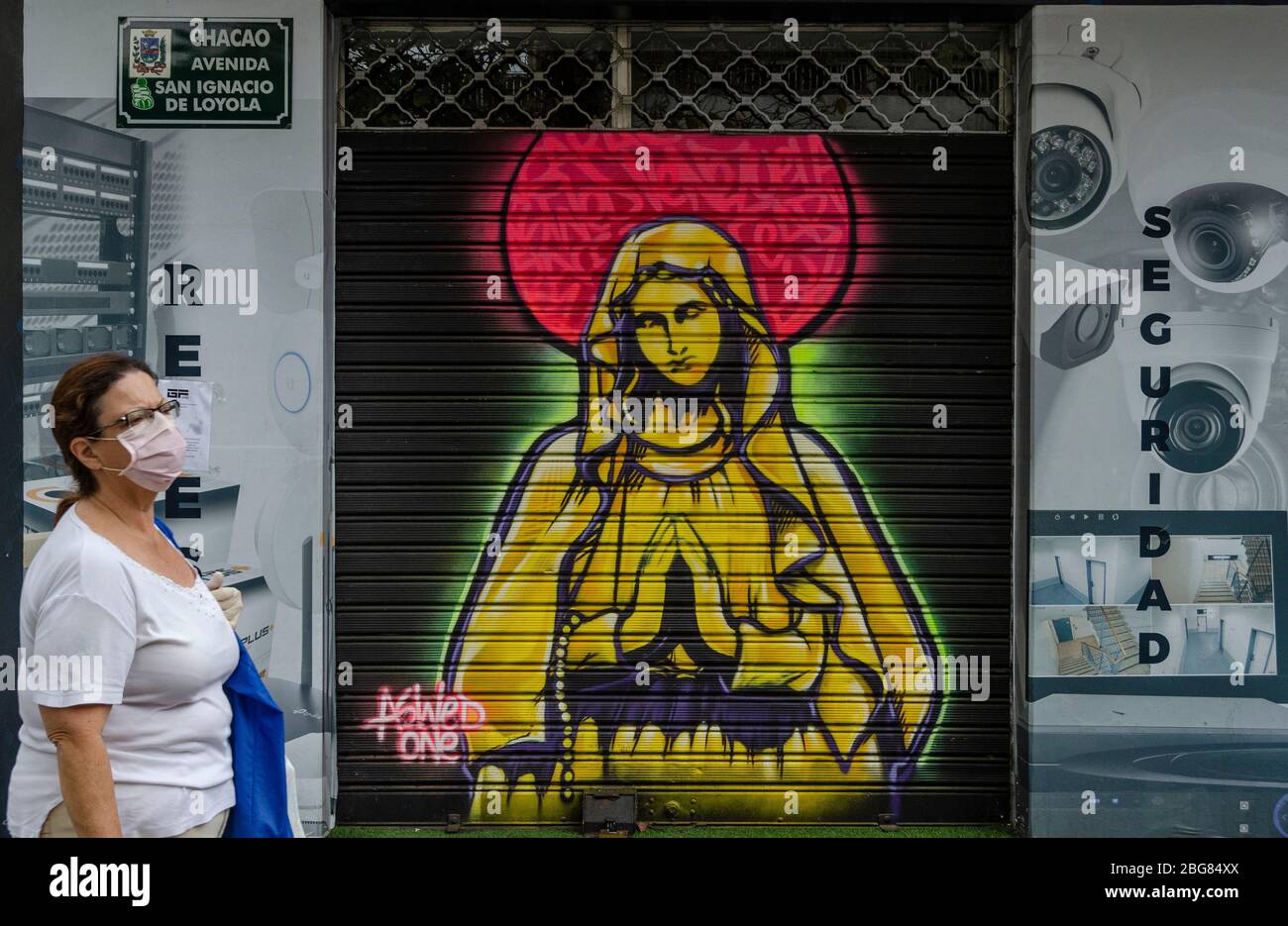 Graffitis de la Vierge Marie dans une rue de Caracas en tant que femme portant l'embout buccal obligatoire passe par en raison de la pandémie de Covid-19 Banque D'Images
