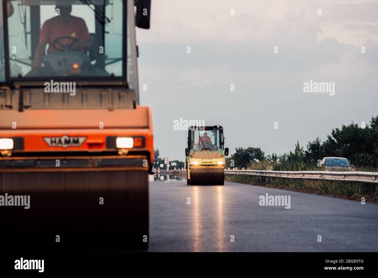 Un travailleur roulant applique une nouvelle surface d'asphalte. Chantier de construction de revêtement d'asphalte sur une route Banque D'Images