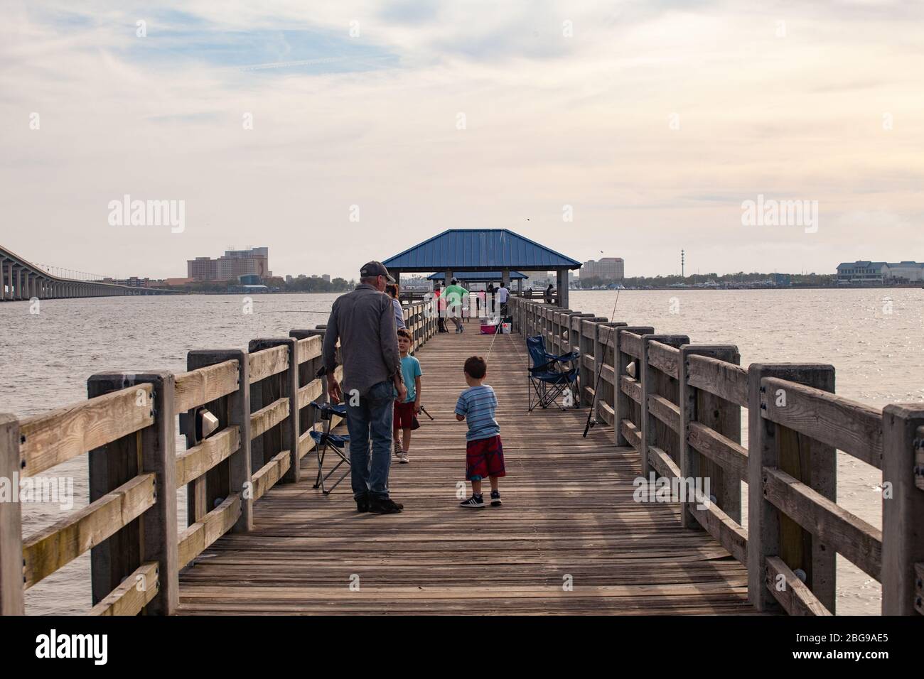 Un homme parle à deux jeunes garçons sur un quai de pêche au-dessus de Biloxi Bay, Ocean Springs, Mississippi, États-Unis Banque D'Images