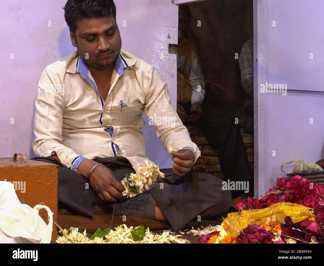 DELHI, INDE - 12 MARS 2019: Travailleur indien masculin faisant des guirlandes de fleurs dans le vieux delhi Banque D'Images