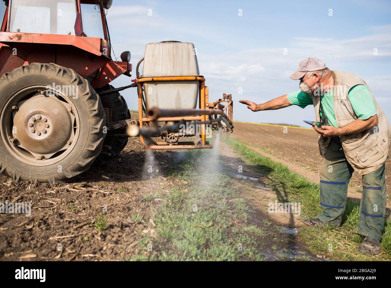 l'agriculteur contrôle le fonctionnement du pulvérisateur. l'agronome utilise la technologie moderne dans ses champs. l'agriculteur utilise la tablette pendant les travaux sur le terrain Banque D'Images