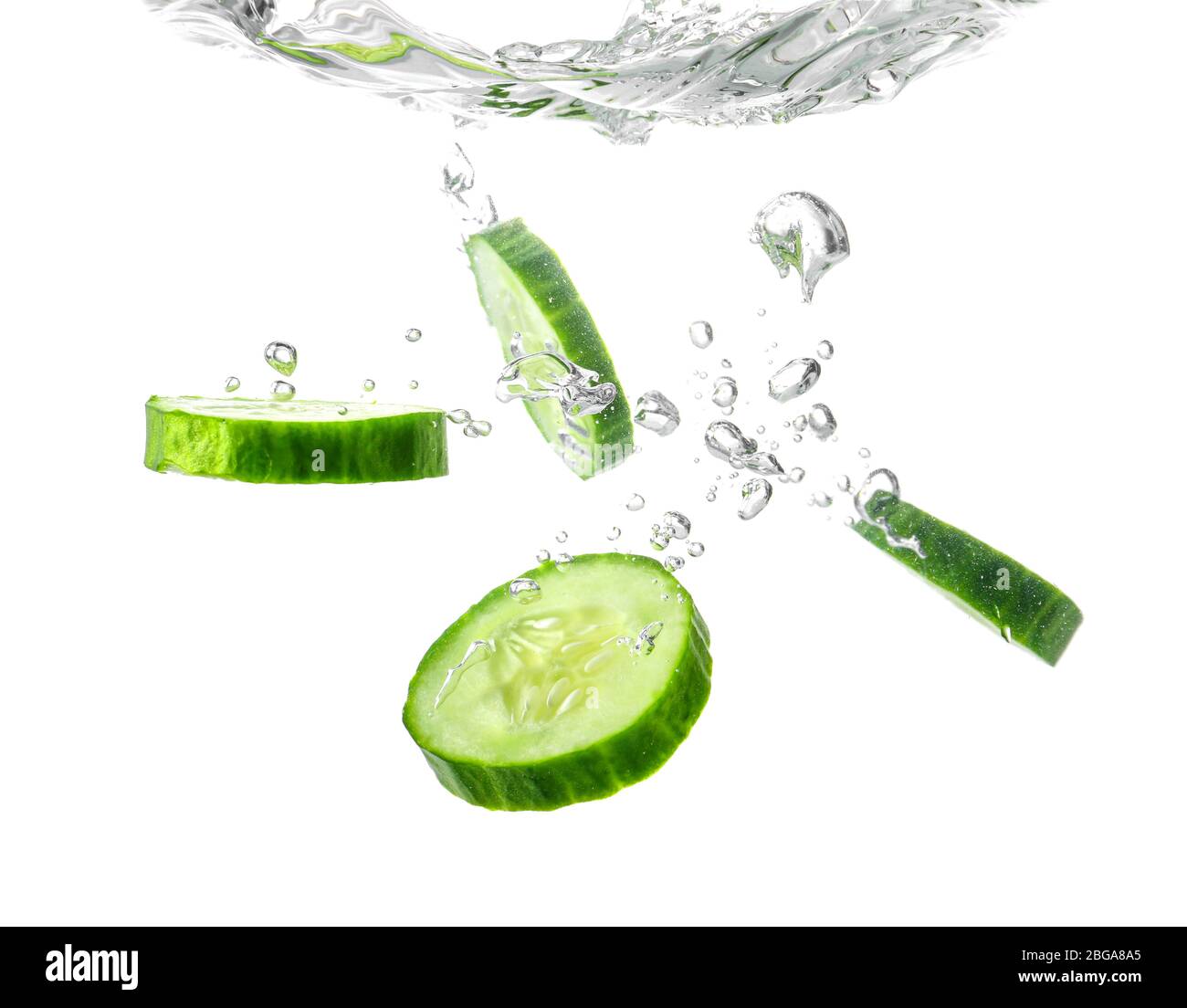 Chute de tranches de concombre frais dans l'eau sur fond blanc Banque D'Images