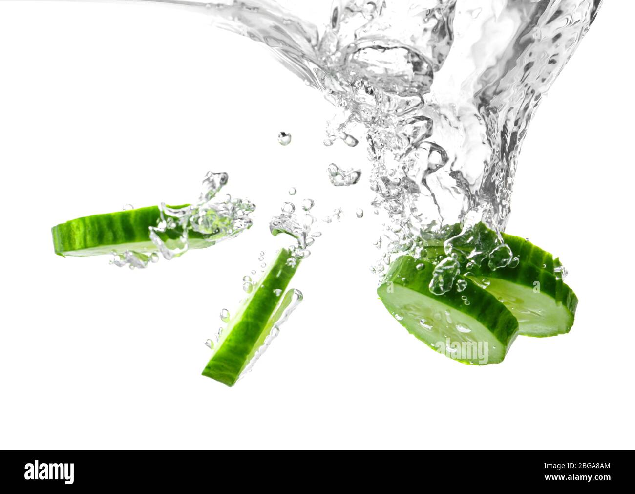Chute de tranches de concombre frais dans l'eau sur fond blanc Banque D'Images