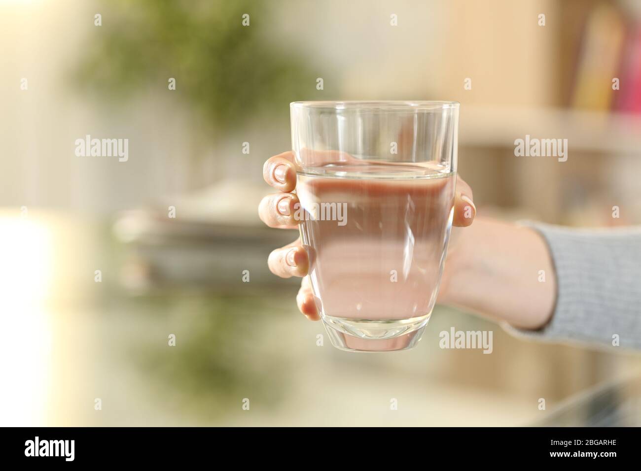 Gros plan de la main de fille tenant un verre d'eau filtrée à la maison Banque D'Images