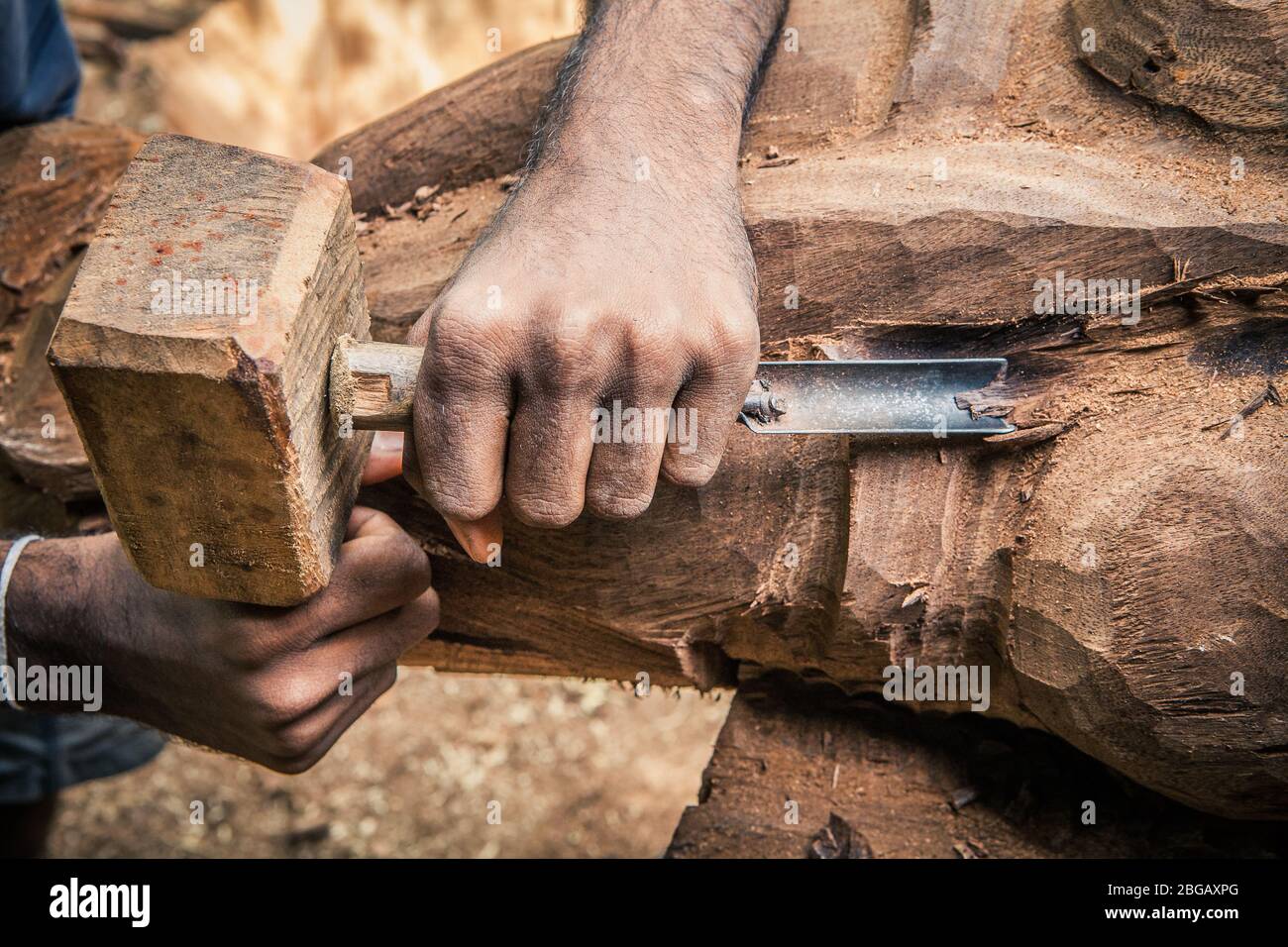 Bois de travail de charpentier. Outils rudimentaires. Deux mains ciseant un morceau de bois. Banque D'Images