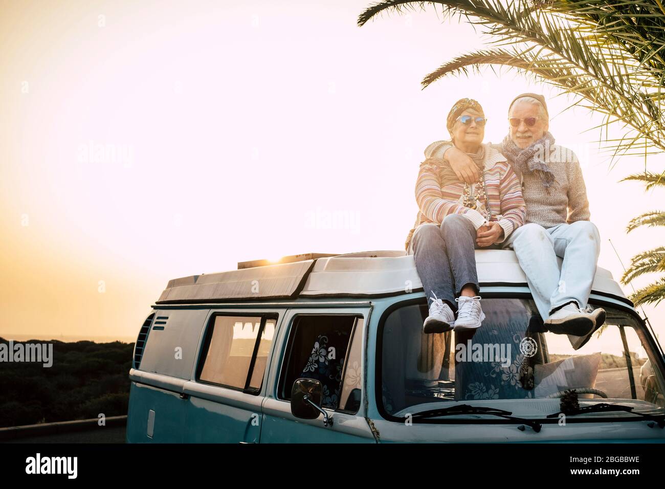 Deux vieux voyageurs s'assoient ensemble sur le toit de la fourgonnette, profitez du coucher du soleil avec amour - pour toujours et concept de vacances pour tr Banque D'Images