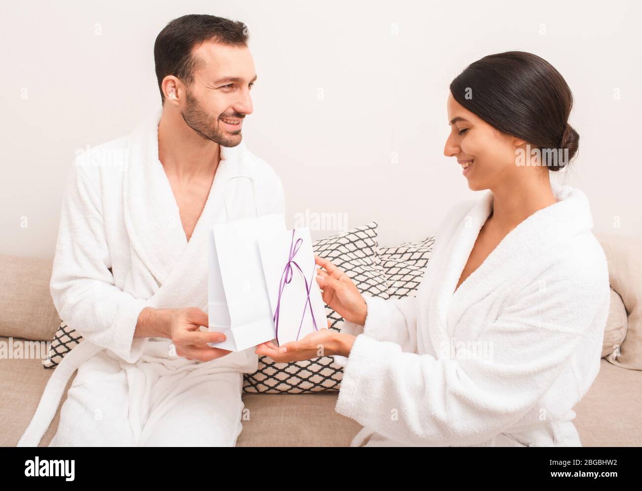 Un beau couple est très heureux avec un cadeau du certificat du salon de spa pour les visites de massage et de sauna. Homme et femme portant dans des peignoirs Banque D'Images